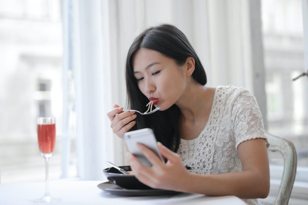 Woman eating while watching on her phone